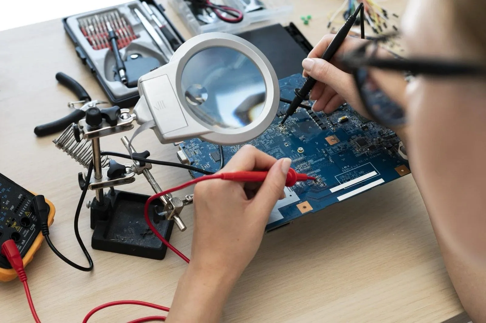 An engineer testing a circuit board with multimeter probes under a magnifier